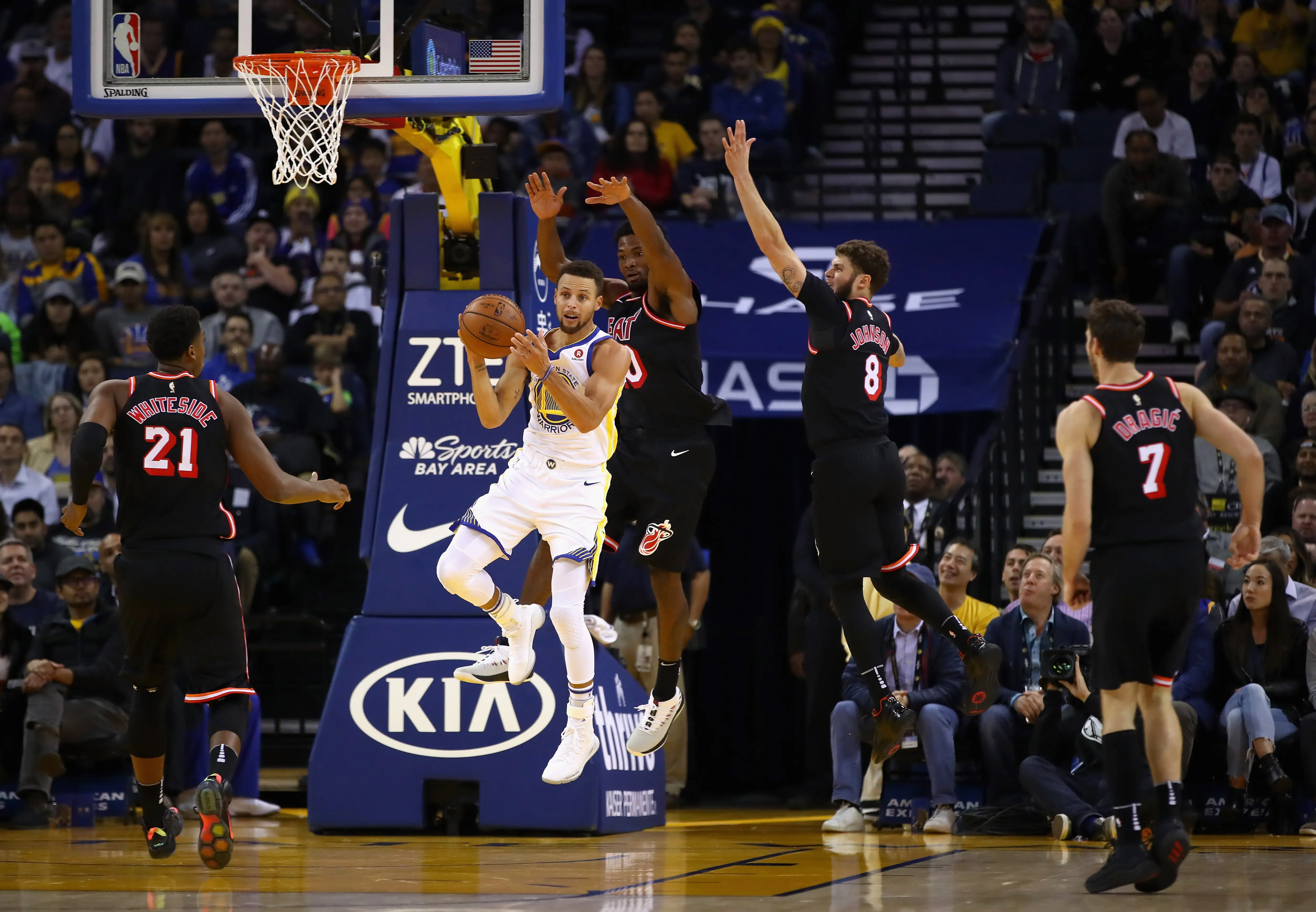 Guard Golden State Warriors, Stephen Curry, mengumpan bola dari kepungan pemain Miami Heat pada laga NBA 2017-2018 di Oracle Arena, Senin (6/11/2017) atau Selasa (7/11/2017) pagi WIB. (AFP/Ezra Shaw)