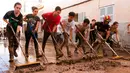 Warga dibantu petugas membersihkan lumpur di jalan usai banjir bandang melanda daerahnya di Sant Llorenc, Mallorca, Spanyol (11/10). Banjir bandang tersebut telah menewaskan setidaknya 10 orang. (AP Photo/Francisco Ubilla)