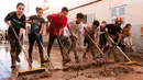 Warga dibantu petugas membersihkan lumpur di jalan usai banjir bandang melanda daerahnya di Sant Llorenc, Mallorca, Spanyol (11/10). Banjir bandang tersebut telah menewaskan setidaknya 10 orang. (AP Photo/Francisco Ubilla)