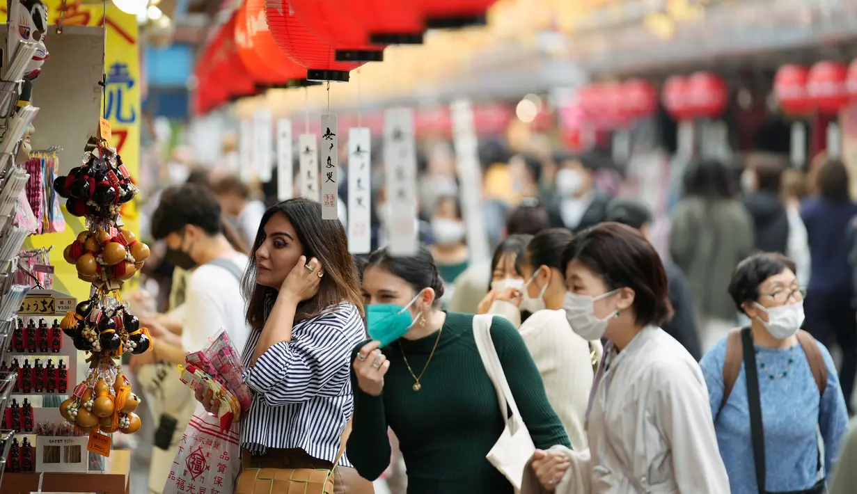 Turis asing berbelanja di toko suvenir dekat kuil Buddha Sensoji di distrik hiburan Asakusa, Tokyo, Jepang, Senin (17/10/2022). Pengunjung termasuk turis asing memadati distrik Asakusa setelah adanya pelonggaran pembatasan karena pandemi virus corona. (AP Photo/Hiro Komae)