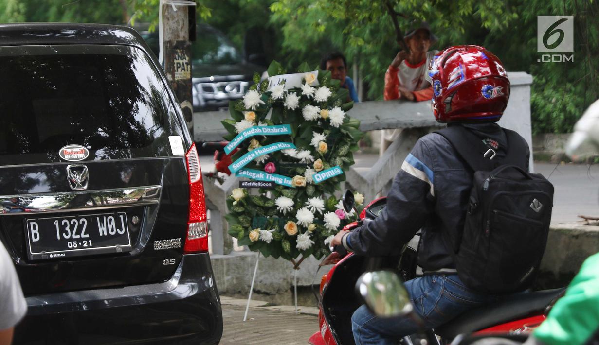 Kendaraan melintas dekat karangan bunga yang bersandar pada tiang lampu di Jalan Permata Berlian, Jakarta, Sabtu (18/11). Tiang itu mendadak menajdi perhatian banyak orang karena ditabrak mobil yang ditumpangi Setya Novanto. (Liputan6.com/Angga Yuniar)