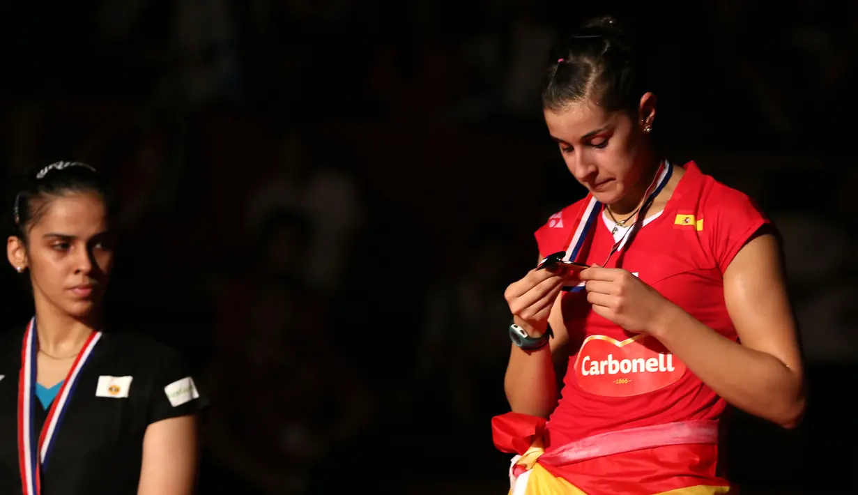 Carolina Marin memperhatikan medali emas yang diraihnya, sementara Saina Nehwal meliriknya. Minggu (16/8/2015). (Bola.com/Arief Bagus)
