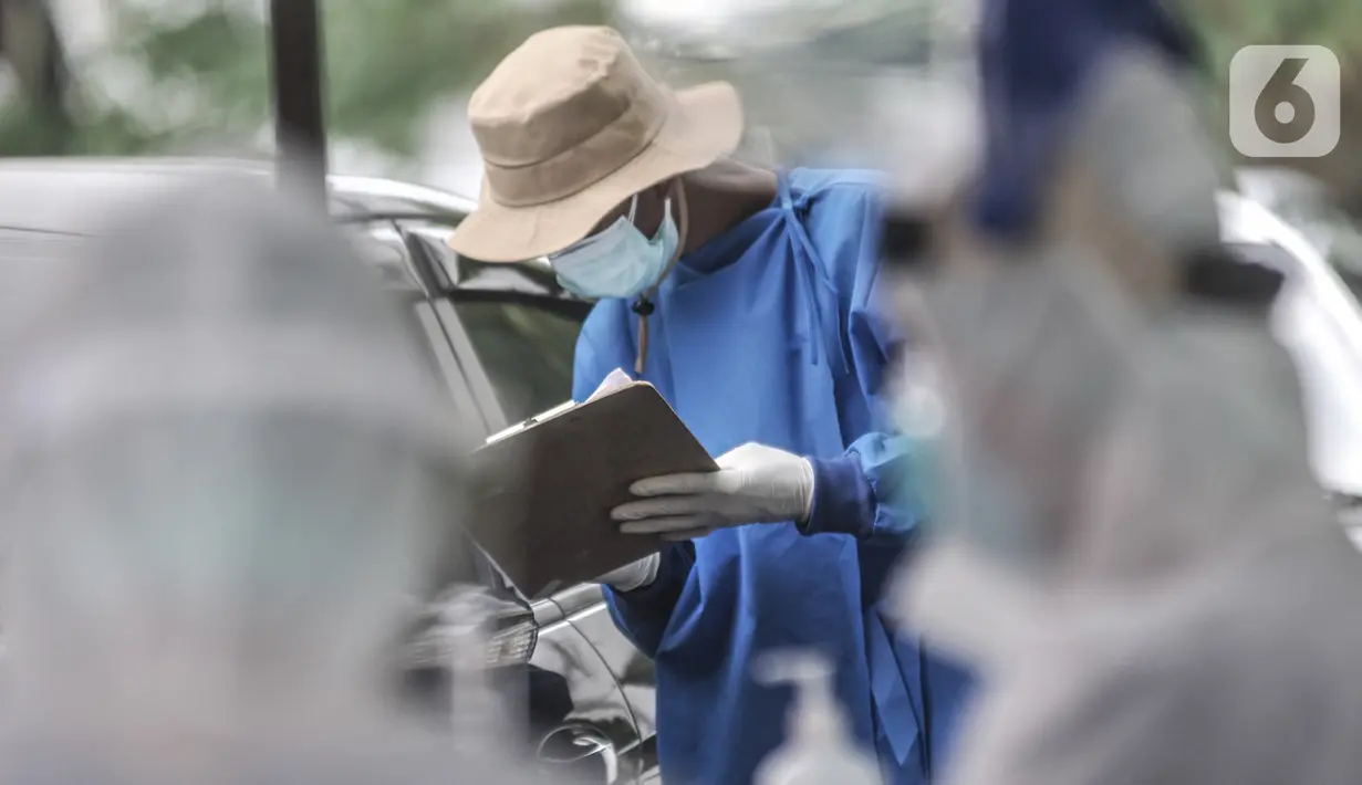 Tenaga kesehatan mendata pengguna mobil sebelum tes usap PCR drive thru di halaman Rumah Sakit Pertamina Jakarta (RSPJ), Rabu (6/1/2021). RSPJ menyediakan layanan tes usap PCR mandiri secara drive thru guna melacak sekaligus memutus penyebaran Covid-19. (merdeka.com/Iqbal Nugroho)