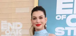 Anne Hathaway tunjukkan pesona bumil edgy dengan atasan asimetris dan jeans (Photo by VALERIE MACON / AFP)
