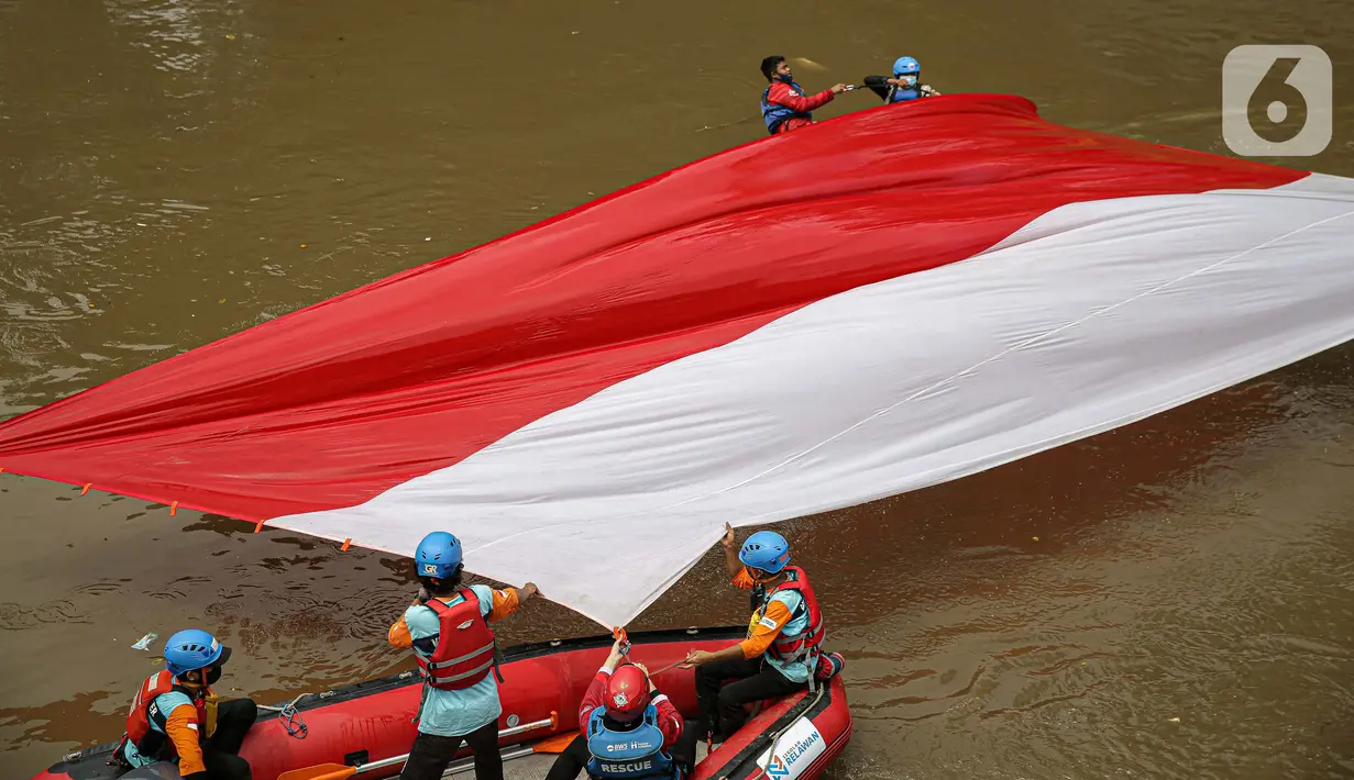 Sejumlah relawan membentangkan bendera Merah Putih di aliran kali
Ciliwung di kawasan Sudirman, Jakarta, Minggu (22/8/2021). Pembentangan atau pengibaran bendera Merah Putih tersebut dilaksanakan untuk memperingati HUT ke-76 RI. (Liputan6.com/Faizal Fanani)