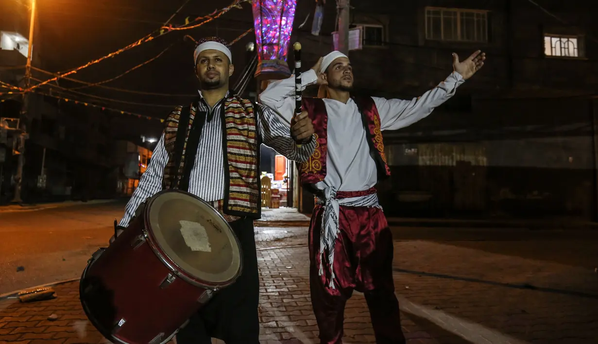 Dua pemuda "Musharati" Palestina memukul gendang saat membangunkan umat muslim untuk sahur pada malam kedua selama bulan suci Ramadan di Rafah di Jalur Gaza selatan (25/4/2020). (AFP/Said Khatib)