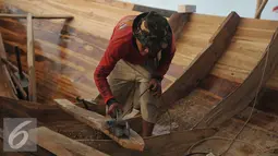 Pekerja menyerut kayu untuk pembuatan kapal kayu berjenis But Tempel di Cilincing, Jakarta, Selasa (9/8). Proses pembuatan kapal kayu tersebut memakan waktu sekitar 2 bulan. (Liputan6.com/Gempur M Surya)