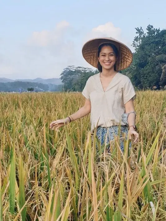 Senyum bahagia tidak bisa disembunyikan Prisia Nasution saat berada di sawah dengan tanaman padi yang terlihat menguning. Dengan memakai caping, ia sangat bahaga berada di antara tanaman padi di sawah. (Liputan6.com/IG/@prisia)