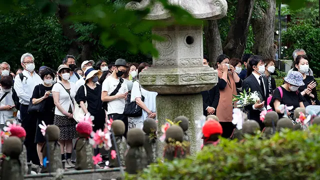 Orang-orang berbaris untuk mempersembahkan bunga dan doa untuk mantan Perdana Menteri Shinzo Abe, di Kuil Zojoji sebelum pemakamannya Selasa, 12 Juli, di Tokyo. (Eugene Hoshiko/AP)
