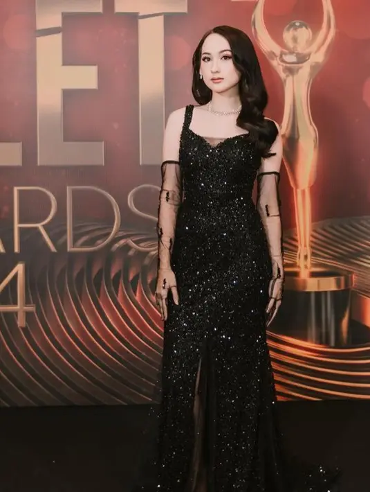 Laura mengenakan slit dress sequin warna hitam membuat tampilan terlihat mewah. Dress yang dibuat oleh Inne Collection ini memiliki squareback sleeveless. Gaunnya ini memiliki bawah cukup panjang menyapu lantai. [@morizsey]
