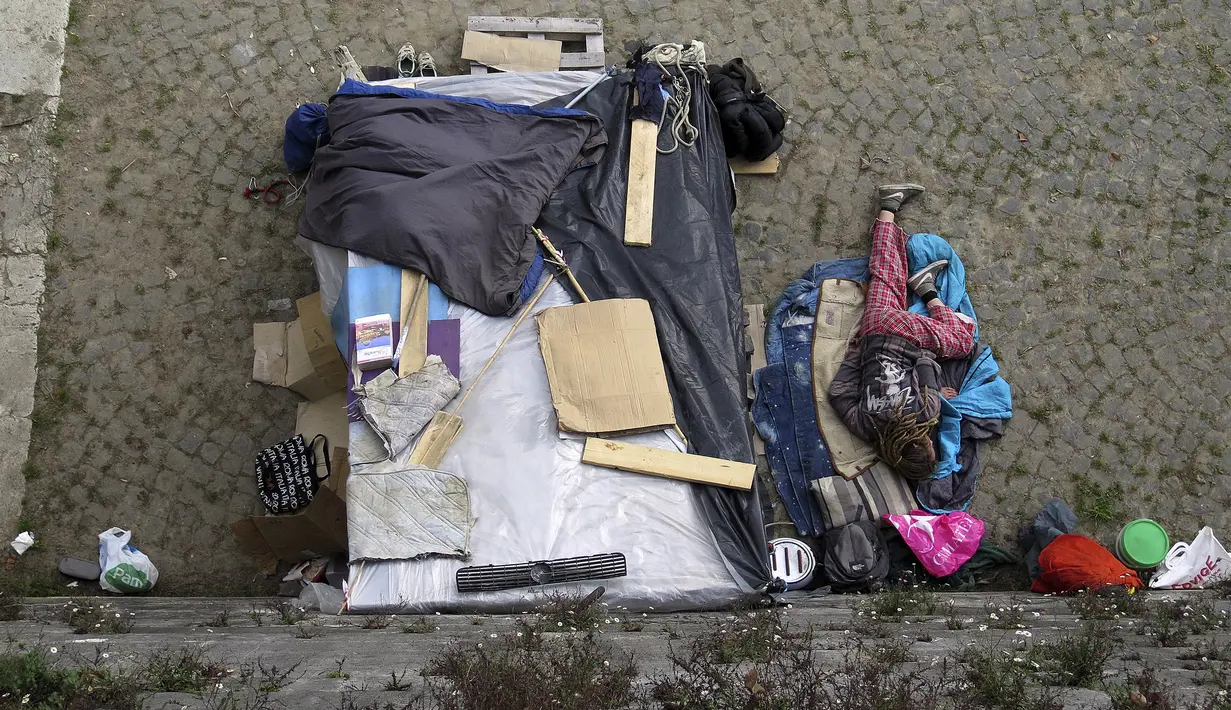 Seorang tunawisma tertidur di samping tendanya di kawasan permukiman kumuh bawah jembatan di Sungai Tiber, Roma, Italia (13/4). Kondisi tempat tinggal para tunawisma tersebut tak jauh beda dengan di Jakarta. (REUTERS / Max Rossi)
