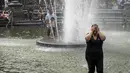 Seorang wanita cuci muka di air mancur saat siang hari yang panas di Washington Square Park di New York City (17/7/2019). Panas terik bergerak ke daerah Kota New York, dengan suhu yang diperkirakan akan mencapai 100 derajat pada akhir pekan ini.  (AFP Photo/Drew Angerer)