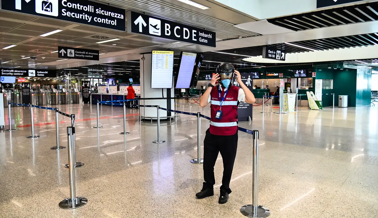 Petugas mengenakan termoscanner portabel "Smart-Helmet" untuk memeriksa suhu penumpang dan sesama staf di terminal keberangkatan bandara Fiumicino Roma, Italia pada 5 Mei 2020. Hal ini dilakukan guna menyaring orang yang memiliki gejala infeksi virus corona. (ANDREAS SOLARO/AFP)