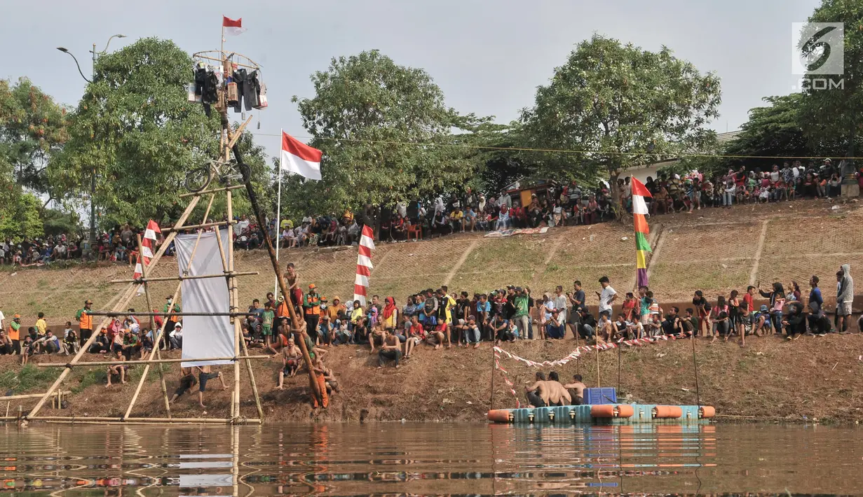 Peserta berusaha mencapai puncak saat lomba panjat pinang dalam rangka HUT ke-74 RI di Kanal Banjir Timur, Jakarta, Sabtu (17/8/2019). Lomba panjat pinang yang diikuti puluhan peserta akhirnya dapat ditaklukkan setelah lebih dari 3 jam para peserta bergelut dengan oli. (merdeka.com/Iqbal S. Nugroho)