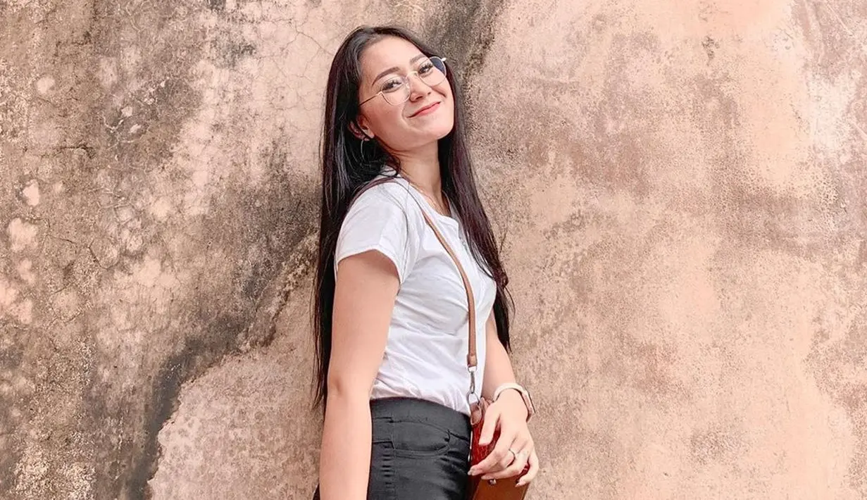Pedangdut berusia 22 tahun ini memang sering tampil santai saat di luar panggung. Gaya kasualnya menggunakan baju kaus putih dengan tas coklat membuatnya terlihat cantik. Tampil menggunakan kacamata membuatnya makin elegan. (Liputan6.com/IG/@iam_vitaalvia)