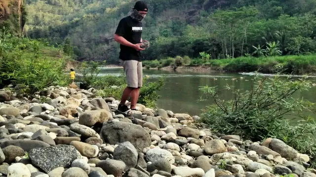 Suryadi sedang mencari batu untuk dibuat batu bertumpuk di salah satusungai diJogja
