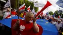 Seorang wanita ikut ambil bagian dalam pawai di jalanan Warsaw, Polandia, Sabtu (7/5). Ribuan warga turun ke jalan memprotes pemerintahan baru Polandia yang dipegang oleh partai konservatif. (REUTERS/Kacper Pempel)