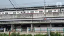 Kereta melintas saat pekerja menyelesaikan pembangunan Stasiun Matraman, Jakarta Timur, Kamis (23/12/2021). Stasiun Matraman yang berada antara Stasiun Manggarai dan Jatinegara ini diharapkan dapat memecah kepadatan penumpang di kedua stasiun tersebut. (merdeka.com/Iqbal S. Nugroho)