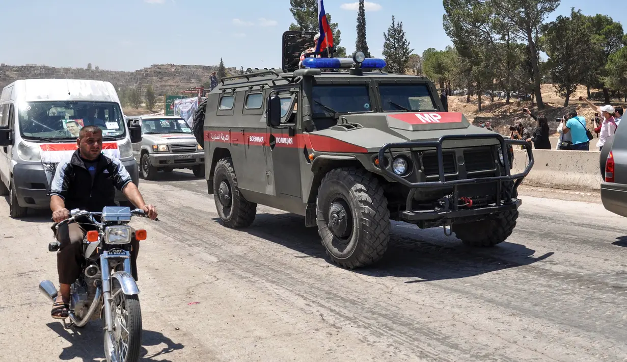 Mobil-mobil pemerintah dan kendaraan militer Rusia melintasi jalan raya utama antara Homs dan Hama di Suriah, Rabu (6/6). Pembukaan jalan itu dilakukan sebulan setelah pasukan Suriah merebut kembali wilayah kantong yang dikuasai militan itu (AFP/STRINGER)