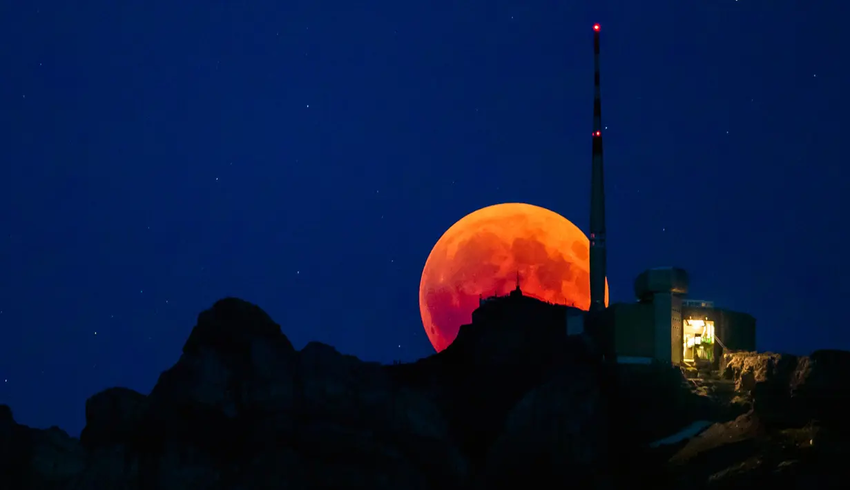 Bulan tampak berwarna merah darah saat terjadinya fenomena gerhana bulan total  di Luzern, Swiss, Jumat (27/7). Gerhana bulan yang terlama pada abad ini dapat disaksikan di seluruh dunia dengan mata telanjang. (Christian Merz/Keystone via AP)