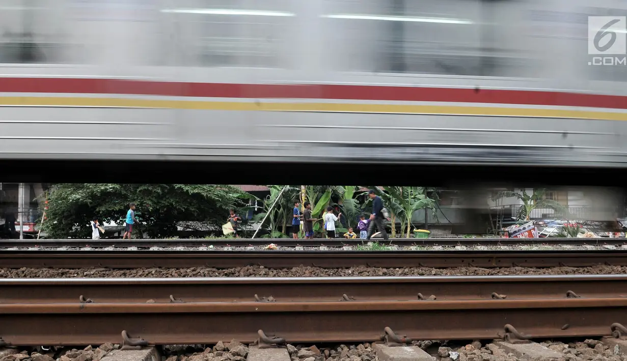 Kereta melintas saat anak-anak bermain di rel kereta api kawasan Jakarta Timur, Kamis (3/1). Minimnya lahan terbuka hijau memaksa anak-anak setempat memilih kawasan rel kereta api sebagai lokasi bermain. (Merdeka.com/Iqbal Nugroho)
