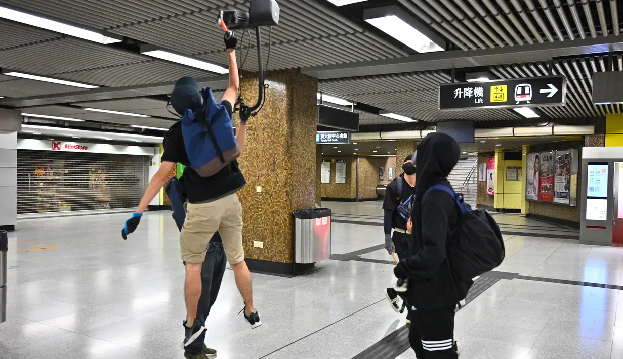 Sejumlah demonstran bertopeng merusak Stasiun MTR Wong Tai Sin di Distrik Kowloon, Hong Kong, Senin (7/10/2019). Demonstran bertopeng merusak beberapa stasiun MTR di Hong Kong. (Philip FONG/AFP)