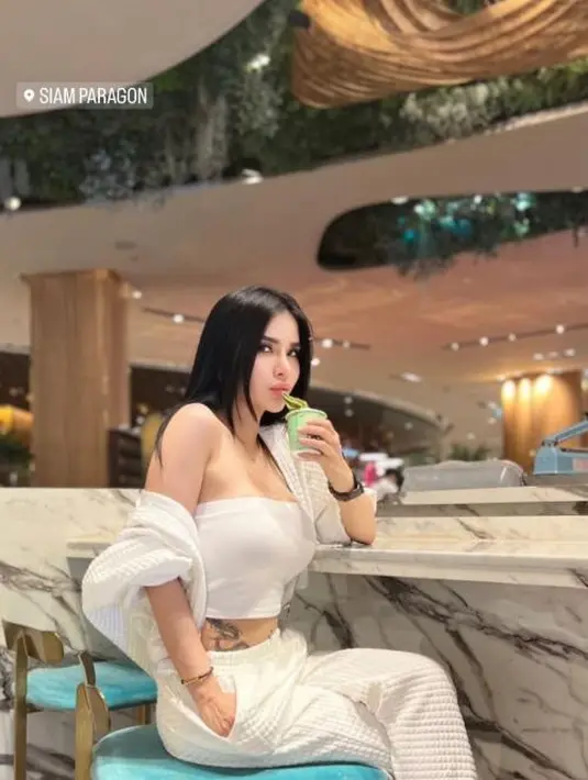 Maria Vania saat mengunjungi Siam Paragon yang merupakan salah satu mal terbesar di Thailand. Maria Vania berpose sambil duduk menikmati es krim. Tak hanya outfit kece, tato naga di perut Vania juga bikin salfok. (Instagram/maria_vaniaa)