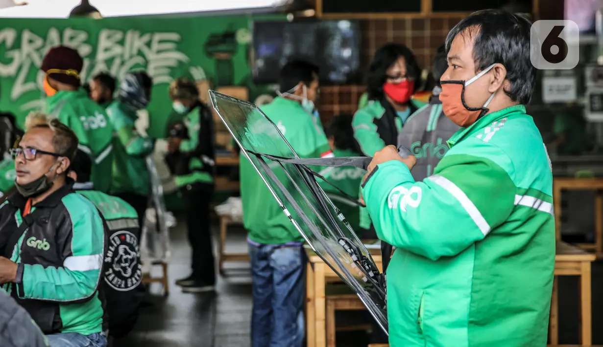 Driver Grab Bike membawa Grab Protect pelindung yang membatasi antara pengemudi dan penumpang di Jakarta, Selasa (9/6/2020). Grab memberikan pengamanan dengan Grab Protect bagi pengemudi yang membatasi antara driver dan penumpang untuk meminimalisir penyebaran COVID-19.  (Liputan6.com/Faizal Fanani)
