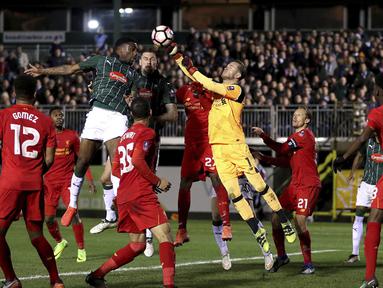 Pemain Plymouth Argyle, Yann Songo'o (atas kiri) berusaha menyundul bola  saat dihadang kiper Liverpool, Loris Karius pada babak ketiga Piala FA di Home Park, Plymouth, (18/1/2017). (Andrew Matthews/PA via AP)