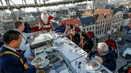Koki menyajikan makan malam untuk para tamu di "Santa in the sky", yang diangkat dengan crane dan dihias menyerupai "Santa Sleigh" sebagai bagian menjelang perayaan Natal di Brussels, Belgia, 25 November 2016. (REUTERS/Yves Herman)