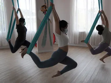 Para murid melakukan gerakan aerial yoga atau yoga udara di Aerial Jooga Studia, Kelapa Dua, Tangerang, Banten, Minggu (10/10/2021). Di masa pandemi, peminat olahraga yang berasal dari Amerika Serikat ini meningkat lebih dari 60 persen. (merdeka.com/Arie Basuki)