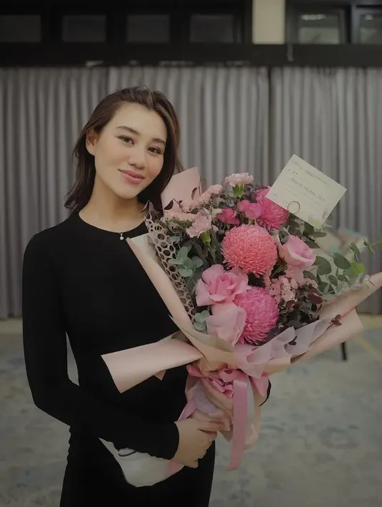 Dapat buket bunga, Aaliyah Massaid tampil effortless beauty dengan slim fit long dress warna hitam. [@aaliyah.massaid].