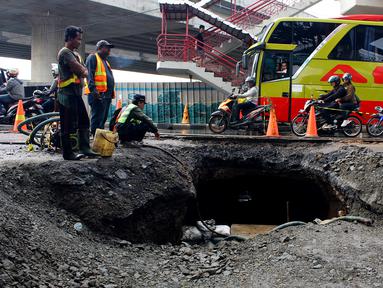 Pekerja memperbaiki jalan ambles di Jalan Daan Mogot, Tangerang, Banten, Senin (13/1/2020). Amblesnya jalan penghubung ke Jakarta ini diduga karena adanya kebocoran pipa PDAM Tirta Kerta Raharja milik Pemkab Tangerang yang mengikis struktur tanah. (merdeka.com/Magang/Muhammad Fayyadh)