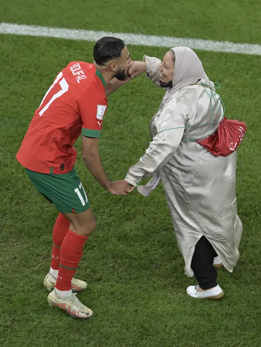 Gelandang Maroko #17 Sofiane Boufal merayakan bersama ibunya setelah lolos ke semifinal dengan mengalahkan Portugal pada babak 8 besar Piala Dunia 2022 di Stadion Al-Thumama di Doha, Sabtu (10/12/2022). Boufal mengajak ibunya berdansa di hadapan suporter di pinggir lapangan. (JUAN MABROMATA / AFP)