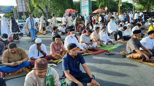 Jemaah salat Id Idulfitri 1443 H terpaksa menggelar sajadah di jalan karena saf di dalam Masjid Raya Baiturrahman telah penuh (Liputan6.com/Rino Abonita)