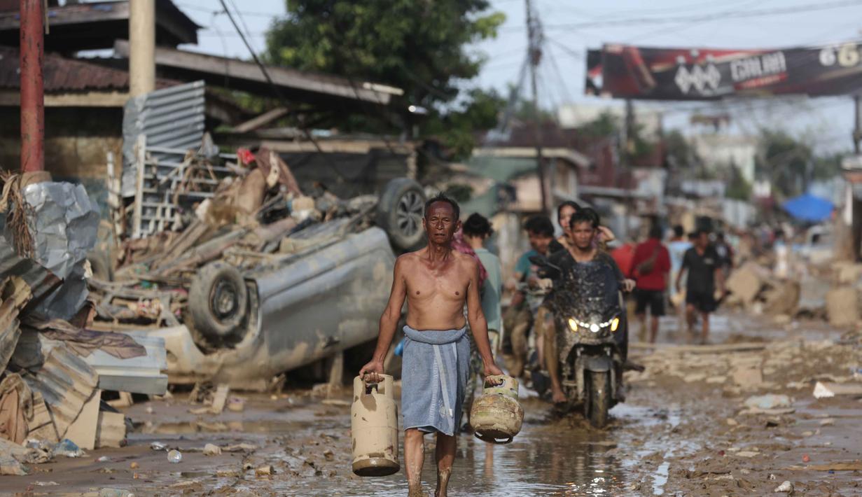 Banyak korban bencana banjir di Kabupaten Aceh Tamiang yang masih belum mendapatkan bantuan logistik berupa makanan. Tampak dalam foto, seorang korban selamat membawa tabung gas bekas di daerah terdampak banjir bandang di Aceh Tamiang, Sumatera, Kamis 4 Desember 2025. (AP Photo/Binsar Bakkara)
