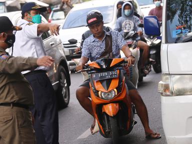 Petugas mengarahkan warga yang terjaring razia penggunaan masker di Kelurahan Sudimara Barat, Kota Tangerang, Kamis (27/5/2021). Mereka yang terjaring razia diminta untuk melakukan tes GeNose C19 guna mencegah penularan virus corona Covid-19. (Liputan6.com/Angga Yuniar)