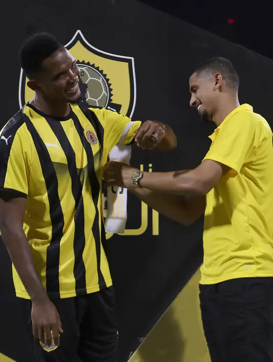 Pemain Qatar Sports Club Fadhl Omar (kan) memberikan band kapten kepada Samuel Eto'o selama presentasi dirinya di Doha, (14/8). Sebelumnya Eto'o membela klub Turki, Konyaspor. (AFP Photo/Karim Jaafar)