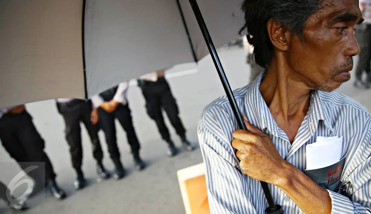 Salah satu peserta Aksi Kamisan membawa payung yang menjadi ciri khas dari aksi tersebut saat berlangsung di depan Istana Negara, Jakarta, Kamis (19/1). (Liputan6.com/ Immanuel Antonius)