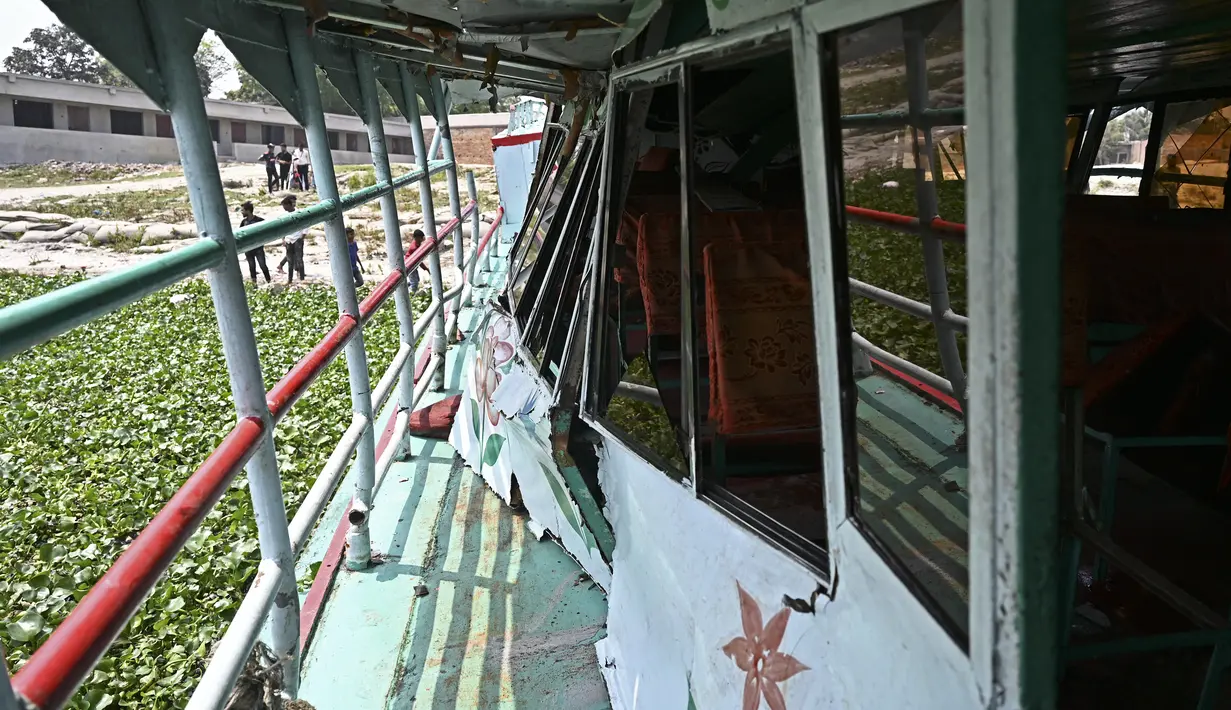 Warga berdiri di dekat bagian yang rusak dari feri yang diselamatkan setelah kecelakaan di Sungai Shitalakshya di Narayanganj, Bangladesh (21/3/2022). Setidaknya enam mayat ditemukan dan 20 orang masih hilang setelah sebuah feri terbalik di sungai Shitalakkhya. (AFP/Munir uz Zaman)