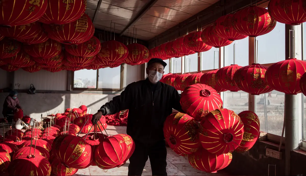 Pekerja membawa lampion yang sudah jadi untuk dijemur jelang perayaan Tahun Baru Imlek di provinsi Hebei, Tingkok (11/1). (AFP Photo/Fred Dufour)