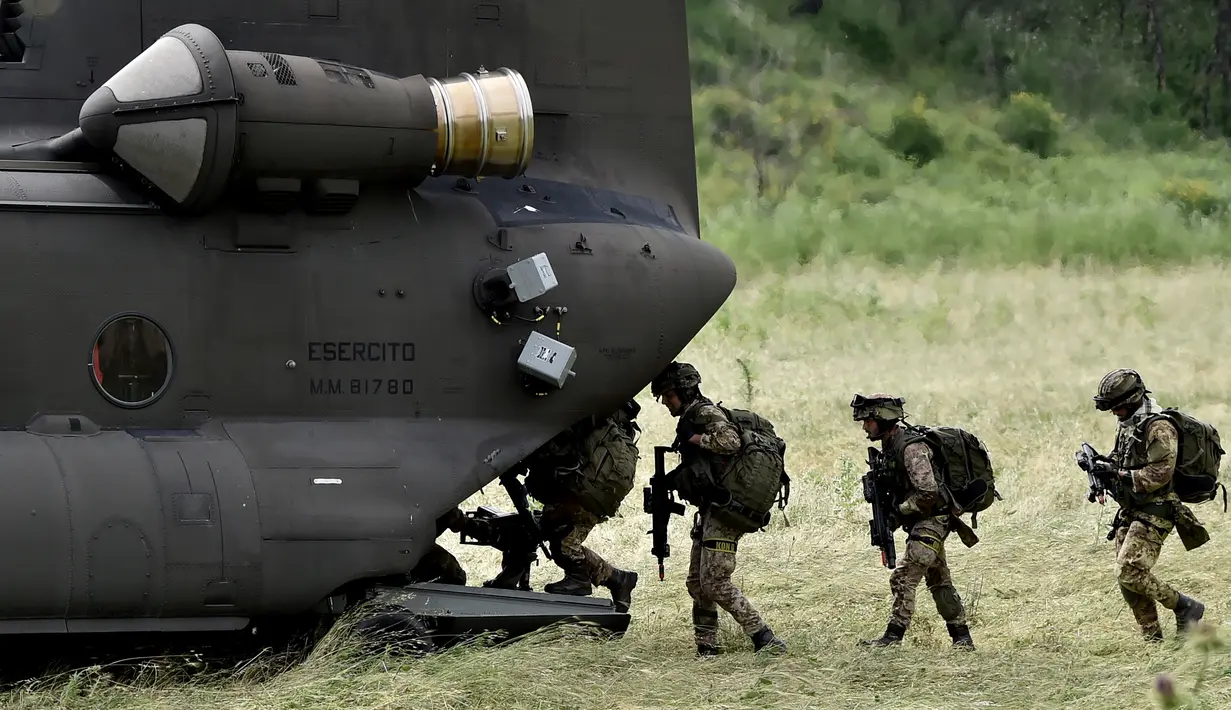 Tentara Italia berjalan menaiki helikopter saat mengambil bagian dalam latihan militer di sebuah kamp pelatihan di Tarquinia, dekat Roma, (21/5).  (AFP Photo/Tiziana Fabi)
