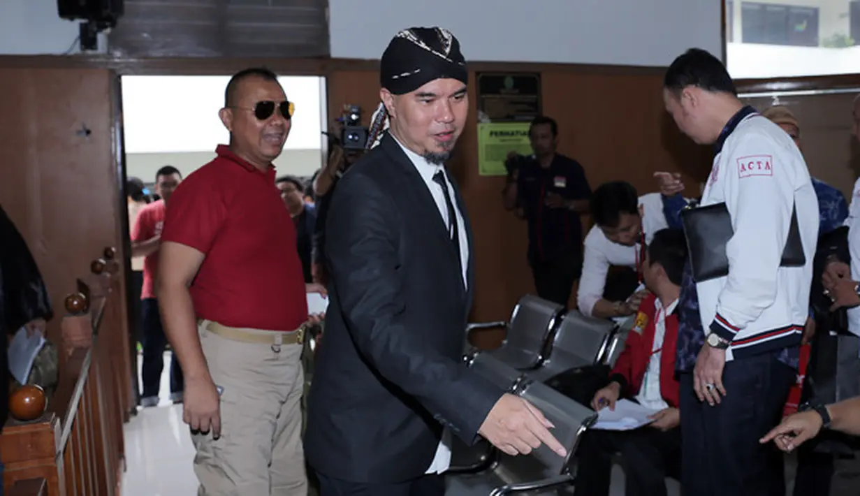 Mengenakan jas warna hitam dan dasi warna serupa. Sedangkan untuk menutup kepalanya yang plontos, ia mengenakan blangkon. (Deki Prayoga/Bintang.com)