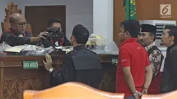 Gatot Brajamusti melihat barang bukti untuk kepemilikan senjata api diruang sidang di PN Jakarta Selatan, Selasa (7/11). Barang bukti itu dikeluarkan jaksa dari tas hitam dan ditunjukkan satu per satu di meja majelis hakim. (Liputan6.com/Herman Zakharia)