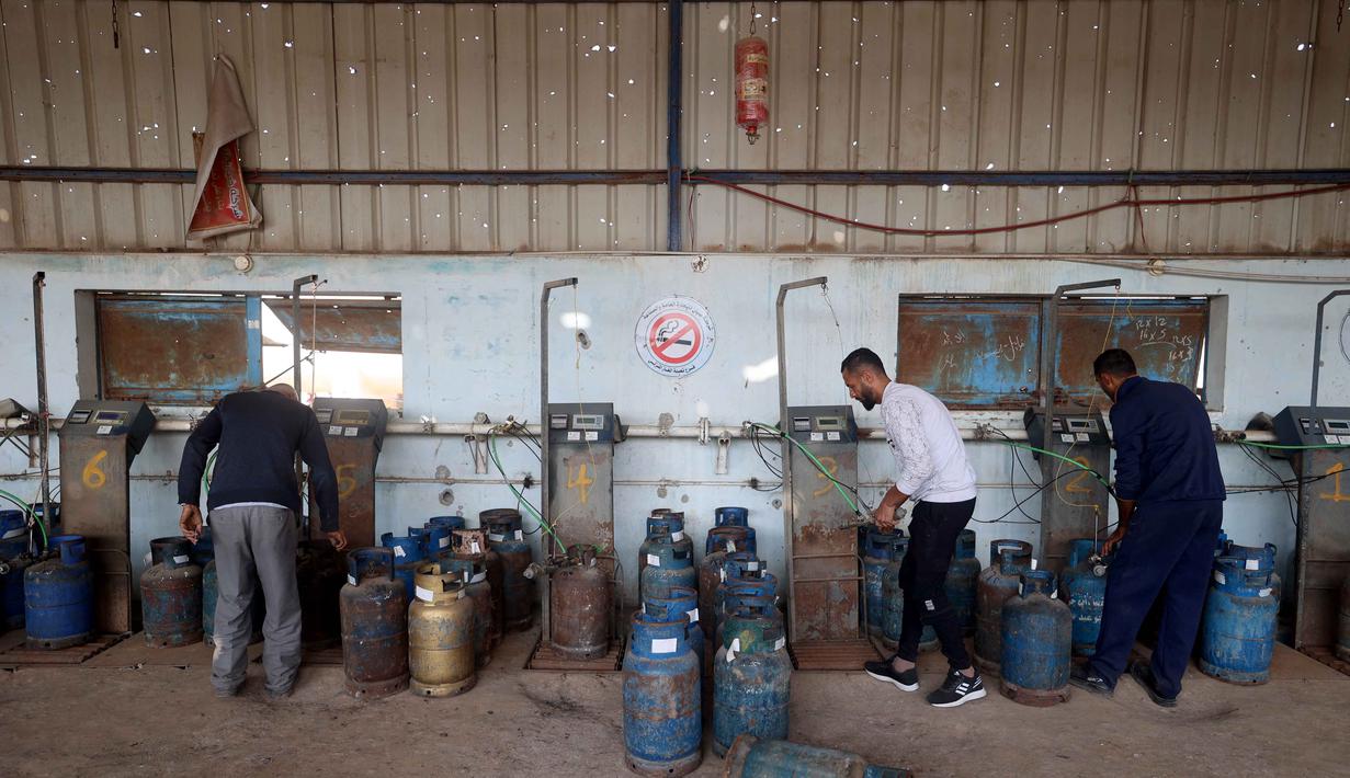 Langkah ini menjadi sinyal awal pelonggaran setelah berbulan-bulan blokade yang membuat warga Gaza hidup dalam krisis kemanusiaan. Tampak dalam foto, pekerja Palestina mengisi tabung gas di stasiun pengisian resmi di kamp pengungsi Nuseirat, di bagian tengah Jalur Gaza, pada 10 November 2025. (Eyad Baba/AFP)