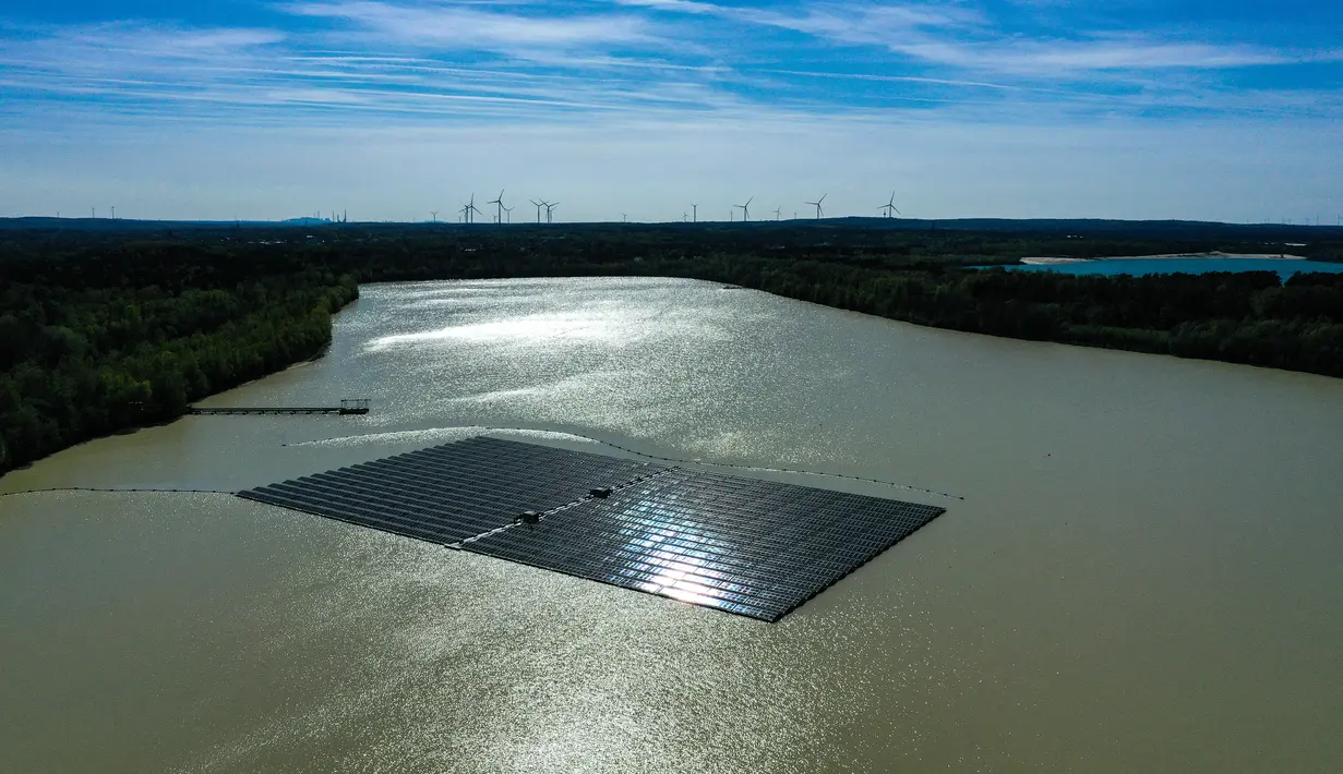 <p>Pemandangan dari udara menunjukkan panel surya dengan turbin angin di kejauhan di pabrik fotovoltaik terapung di danau Silbersee di Haltern, Jerman barat (22/4/2022). Taman surya terapung terbesar di Jerman saat ini sedang dibangun. (AFP/Ina Fassbender)</p>
