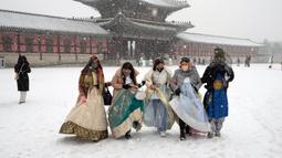 Pengunjung yang mengenakan pekaian tradisional "Hanbok" di salju berjalan melalui Istana Gyeongbok, istana kerajaan utama selama Dinasti Joseon dan salah satu landmark terkenal Korea Selatan di Seoul, Korea Selatan, 15 Desember 2022. (AP Photo/Ahn Young-joon)