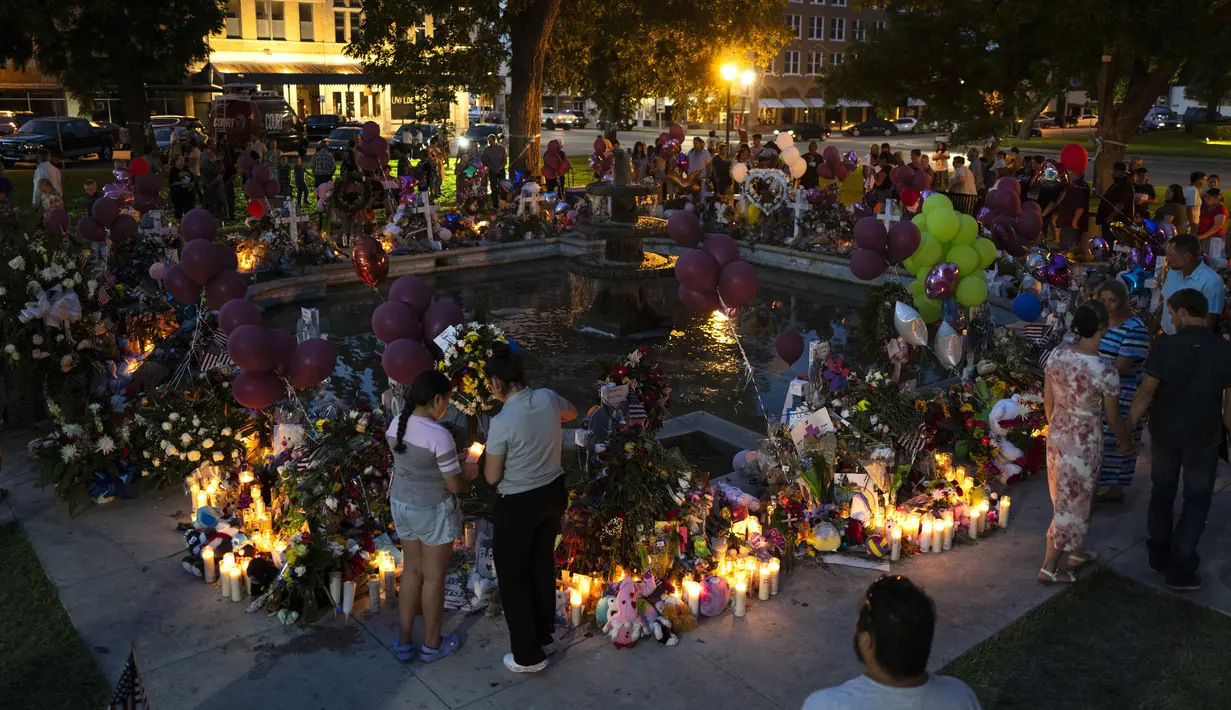 Orang-orang mengunjungi tugu peringatan yang didirikan di alun-alun kota untuk menghormati para korban yang tewas dalam penembakan di sekolah dasar awal pekan ini di Uvalde, Texas, Amerika Serikat, 28 Mei 2022. (AP Photo/Jae C. Hong)