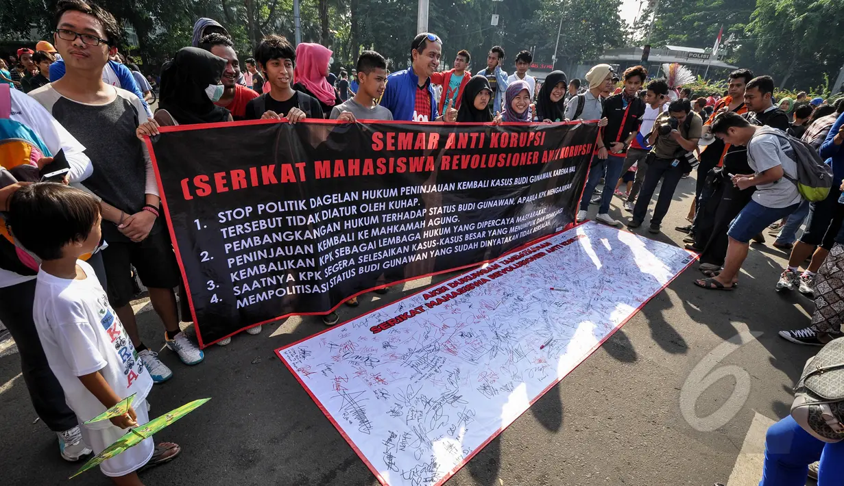 Massa membentangkan spanduk meminta KPK segera fokus menuntaskan kasus-kasus besar saat menggelar aksi di Bundaran HI, Minggu (4/4/2015). Padahal, Pemprov DKI melarang adanya kegiatan bernuansa politik selama CFD berlangsung. (Liputan6.com/Faizal Fanani)