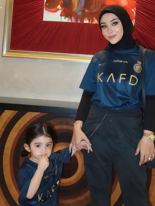 Margin dan putrinya kompak mengenakan jersey navy dari klub Arab, Al Nassr. Ia memadukannya dengan kerudung dan celana hitam. [@marginw]